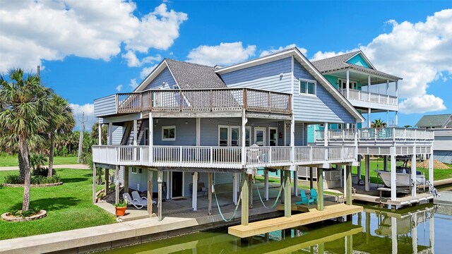 rear view of property with a patio, a lawn, a water view, and boat lift