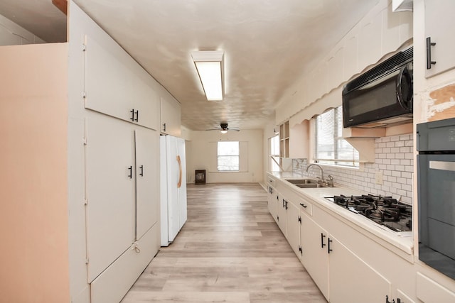 kitchen featuring tasteful backsplash, light countertops, white cabinetry, and black appliances