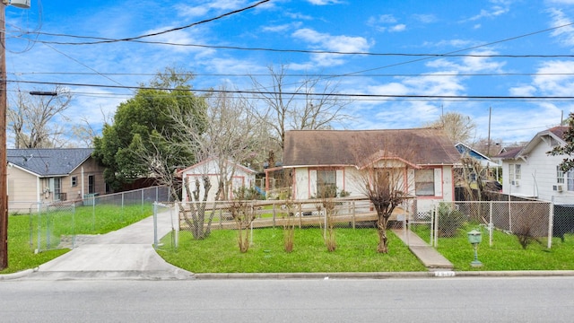 bungalow featuring driveway, a fenced front yard, a residential view, and a front lawn