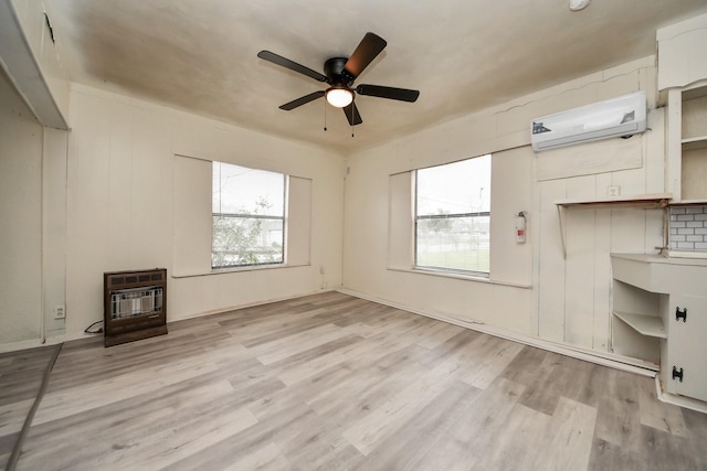 unfurnished living room with ceiling fan, an AC wall unit, light wood-type flooring, heating unit, and a wood stove