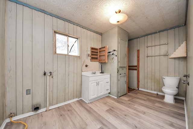 bathroom featuring an ornate ceiling, toilet, a sink, wood finished floors, and baseboards