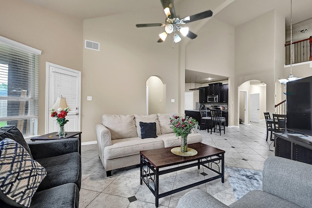 living room featuring arched walkways, light tile patterned flooring, visible vents, and a ceiling fan