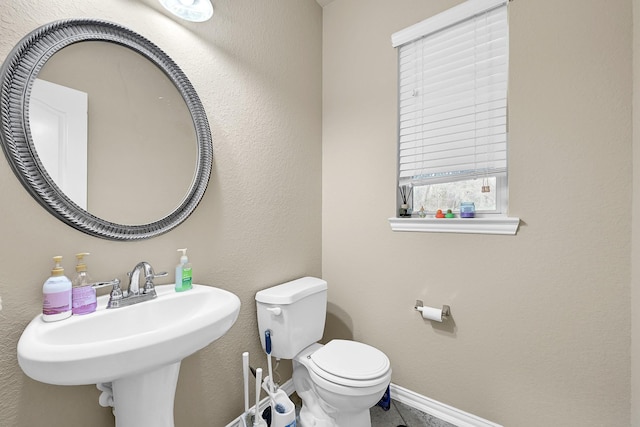 bathroom featuring baseboards, a sink, and toilet