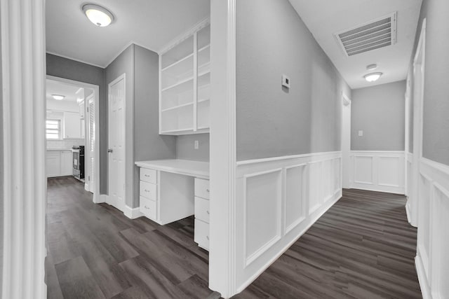 hallway with dark wood-style floors, a wainscoted wall, and visible vents