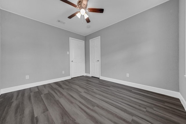 spare room with ceiling fan, baseboards, visible vents, and dark wood finished floors