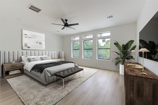 bedroom with light wood-type flooring, ceiling fan, visible vents, and baseboards