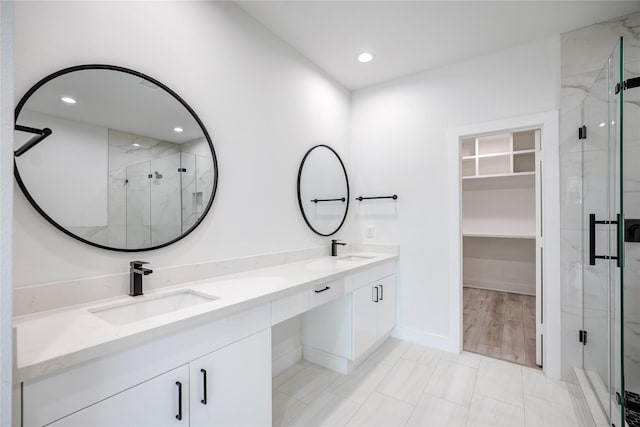 full bath featuring a stall shower, a spacious closet, and a sink