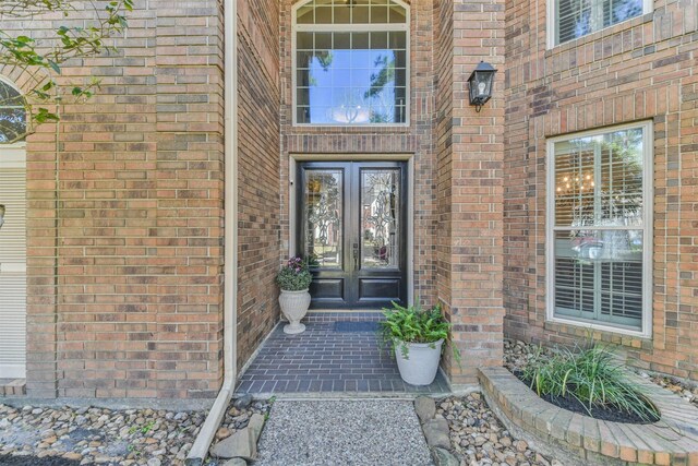 property entrance featuring french doors and brick siding