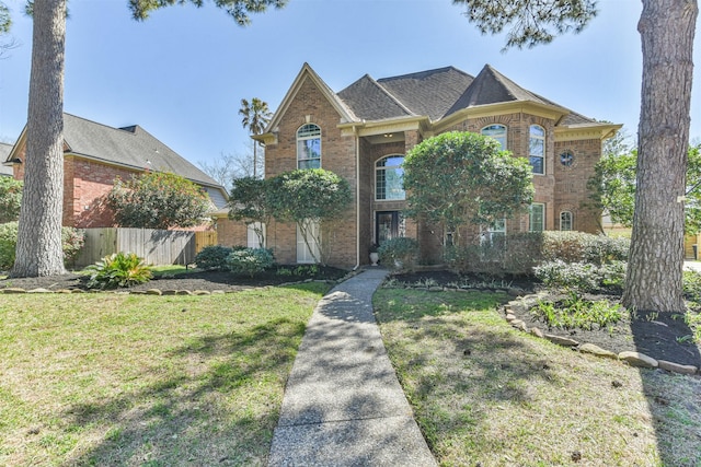 view of front of home with fence, a front lawn, and brick siding