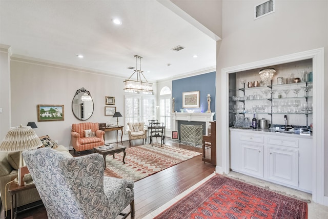 living area featuring visible vents, crown molding, and light wood-style flooring