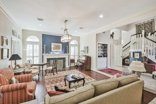 living room with visible vents, stairway, ornamental molding, wood finished floors, and a fireplace