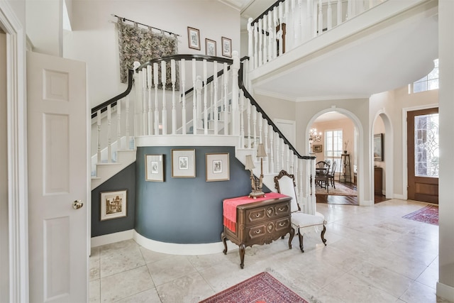 tiled foyer entrance with baseboards, stairs, and arched walkways