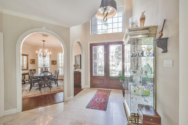 foyer entrance featuring crown molding, a chandelier, a wealth of natural light, and french doors