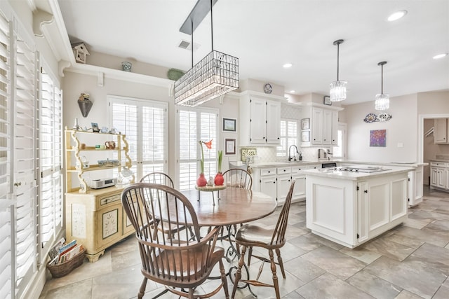 kitchen featuring a sink, light countertops, decorative backsplash, and white cabinets