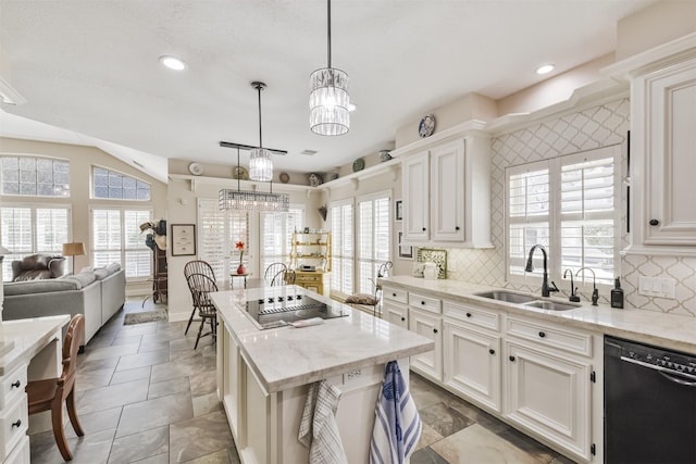 kitchen with light stone countertops, a sink, a center island, black appliances, and an inviting chandelier