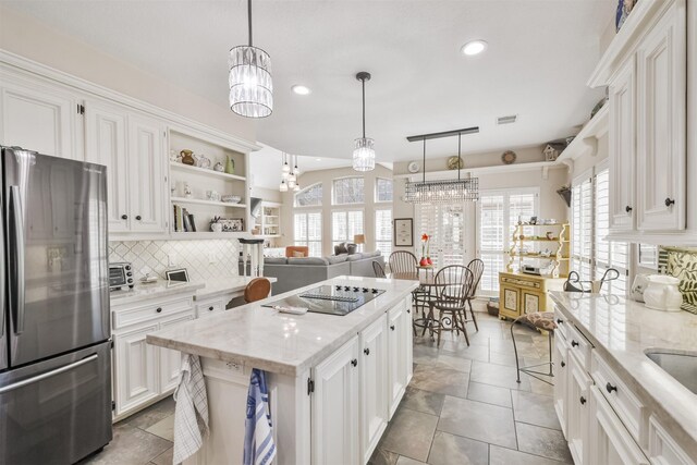 kitchen with black electric stovetop, a kitchen island, white cabinetry, freestanding refrigerator, and open shelves