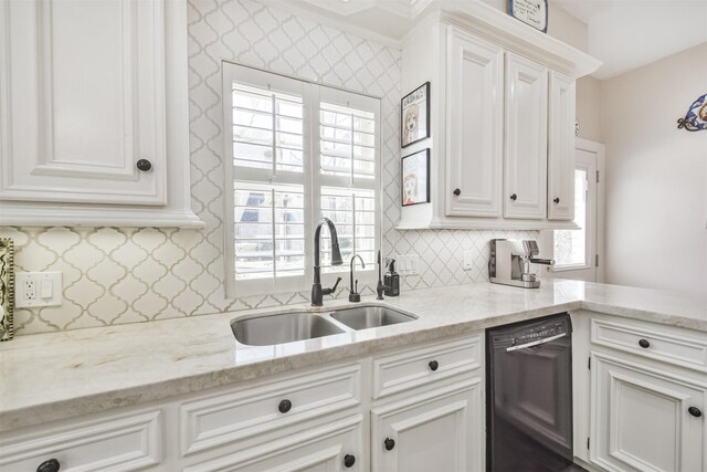 kitchen featuring black dishwasher, tasteful backsplash, light stone countertops, white cabinetry, and a sink