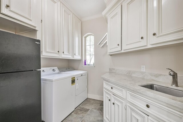 laundry area with a sink, baseboards, ornamental molding, independent washer and dryer, and cabinet space