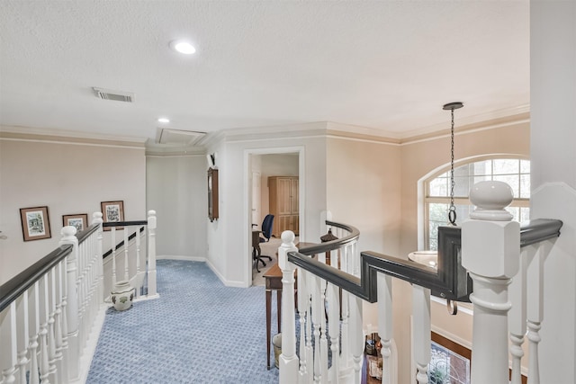 hallway featuring visible vents, ornamental molding, and an upstairs landing