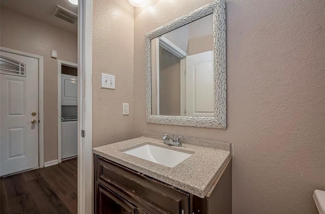 bathroom featuring visible vents, a textured wall, vanity, and wood finished floors