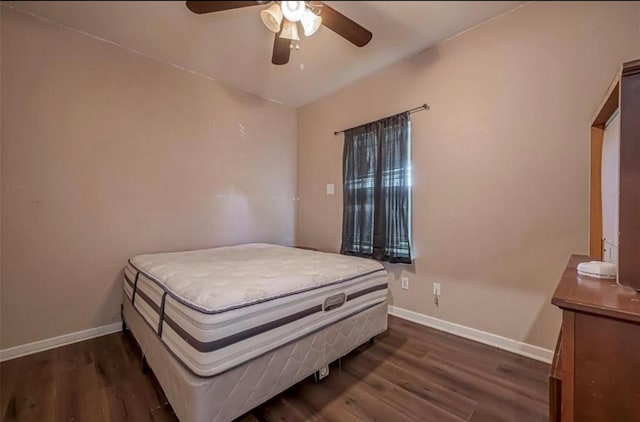 bedroom with dark wood-type flooring, a ceiling fan, and baseboards