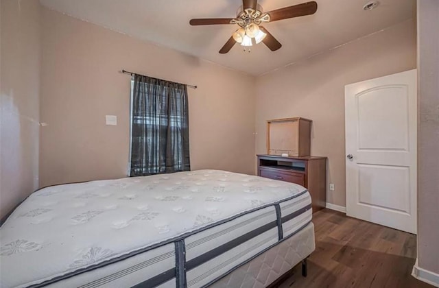 bedroom with dark wood-style floors, ceiling fan, and baseboards