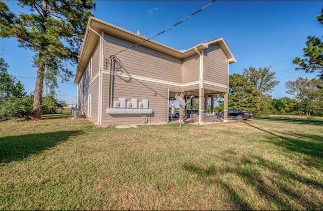 back of house featuring cooling unit, a patio area, and a lawn