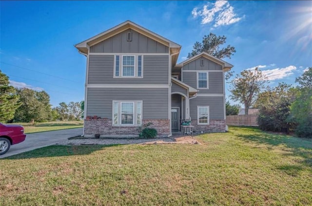 view of front of house with brick siding, fence, concrete driveway, a front lawn, and board and batten siding