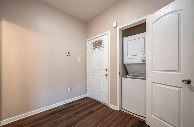 laundry area featuring stacked washer and clothes dryer, dark wood finished floors, and baseboards