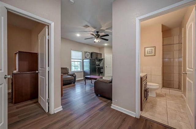 corridor with baseboards, visible vents, and light wood-style floors