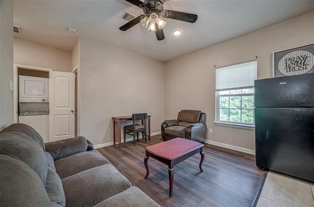 living area with stacked washer and dryer, baseboards, visible vents, and wood finished floors