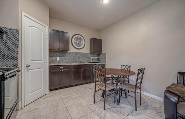 kitchen featuring dark brown cabinetry, stainless steel microwave, black stove, and backsplash