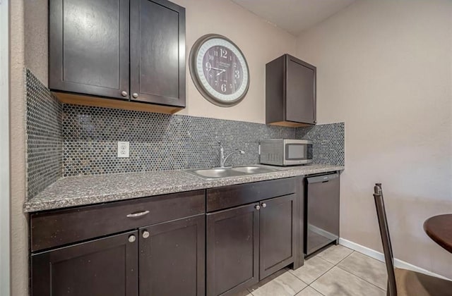 kitchen with a sink, stainless steel appliances, dark brown cabinets, backsplash, and light tile patterned flooring