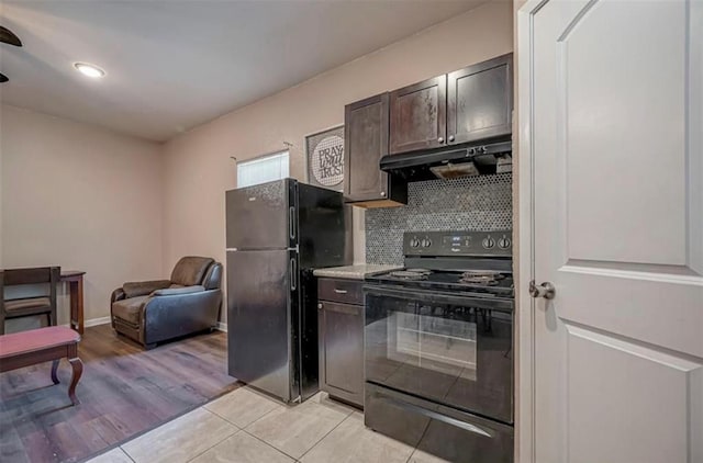 kitchen with light countertops, dark brown cabinetry, under cabinet range hood, and black appliances