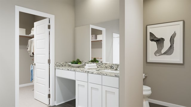 bathroom featuring a closet, toilet, vanity, and baseboards