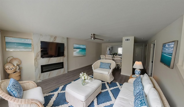 living area with a textured ceiling, a premium fireplace, visible vents, and dark wood-style flooring