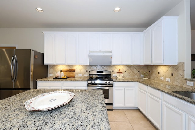 kitchen with white cabinets, light tile patterned floors, light stone counters, and stainless steel appliances