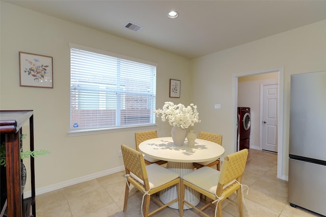 dining room featuring washer / dryer, visible vents, baseboards, and light tile patterned floors