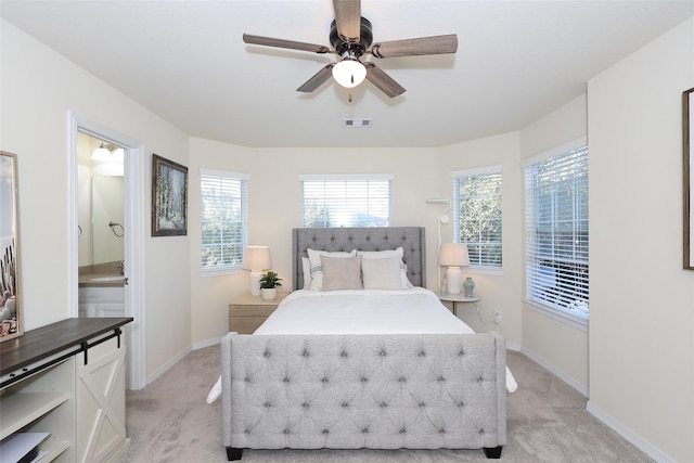 bedroom featuring ensuite bath, baseboards, visible vents, and light colored carpet