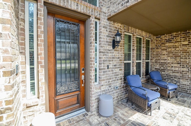 property entrance with a porch and brick siding