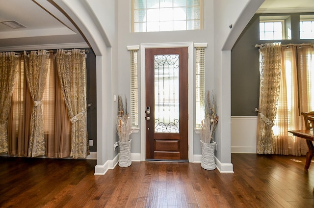 entrance foyer with arched walkways, hardwood / wood-style floors, visible vents, and baseboards