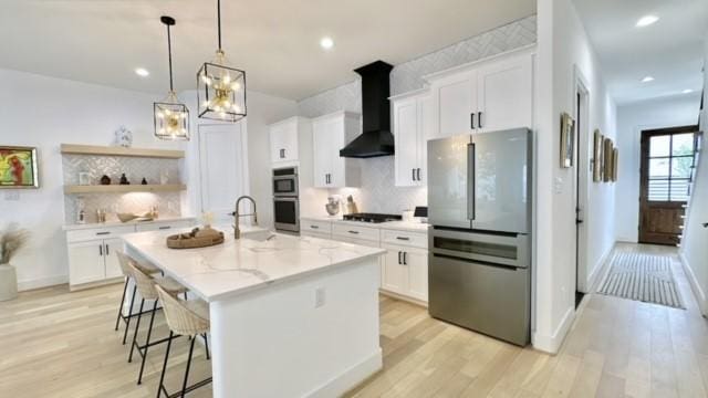 kitchen with stainless steel appliances, white cabinets, wall chimney exhaust hood, and open shelves