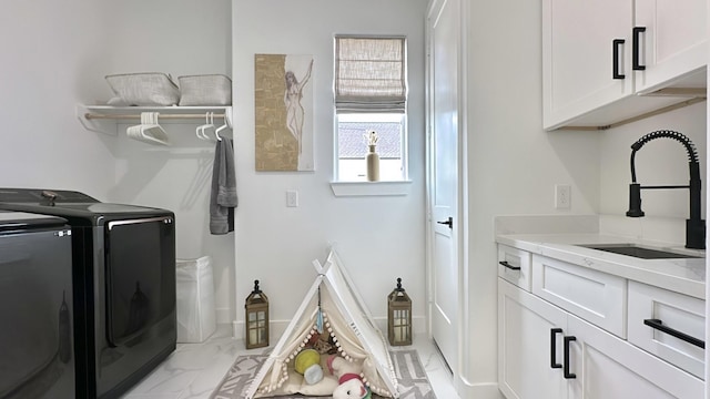 laundry room with cabinet space, baseboards, marble finish floor, washing machine and dryer, and a sink