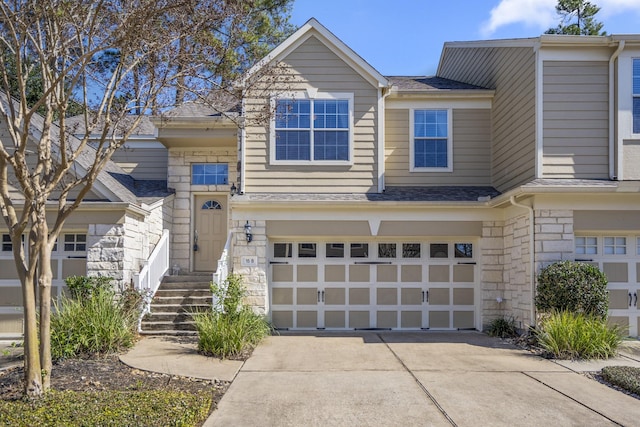 view of front of house featuring an attached garage, stone siding, concrete driveway, and roof with shingles