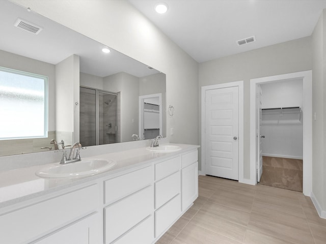 bathroom with a walk in closet, visible vents, and a sink