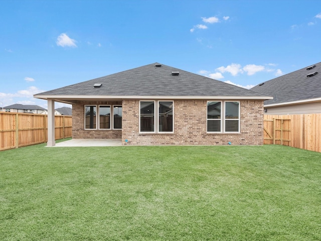 rear view of house featuring a shingled roof, a lawn, a fenced backyard, a patio area, and brick siding