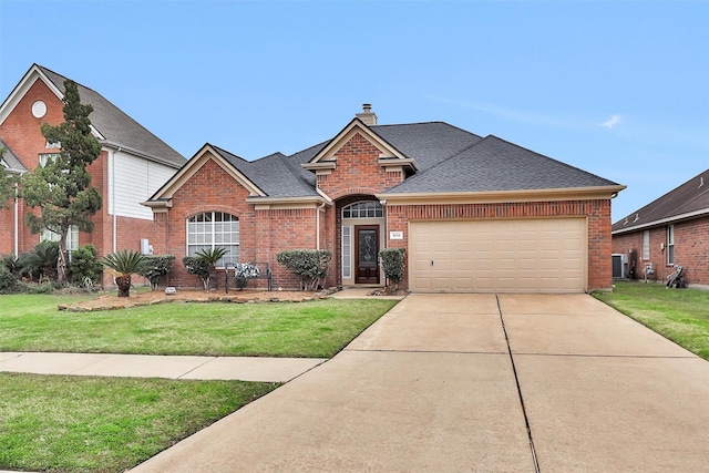 view of front facade featuring brick siding, roof with shingles, a chimney, a front yard, and driveway