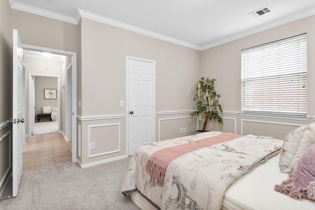 bedroom with attic access, visible vents, light colored carpet, crown molding, and a decorative wall