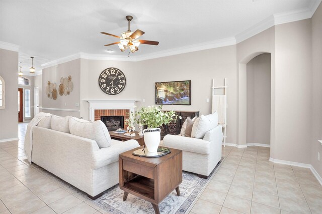 living area featuring a brick fireplace, arched walkways, crown molding, and light tile patterned flooring