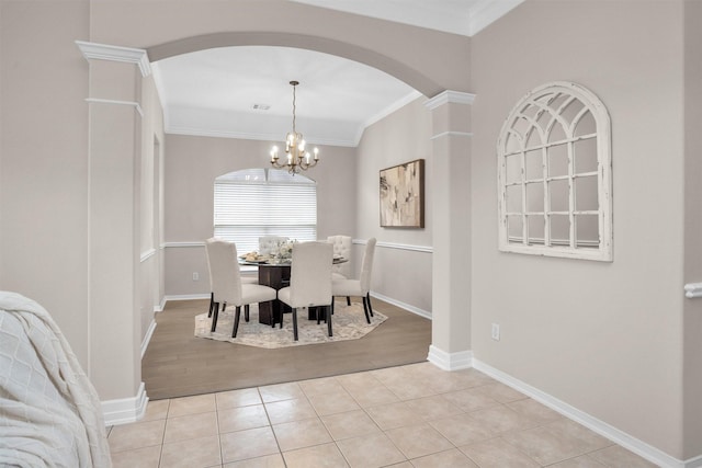 dining room featuring light tile patterned floors, visible vents, baseboards, crown molding, and a chandelier